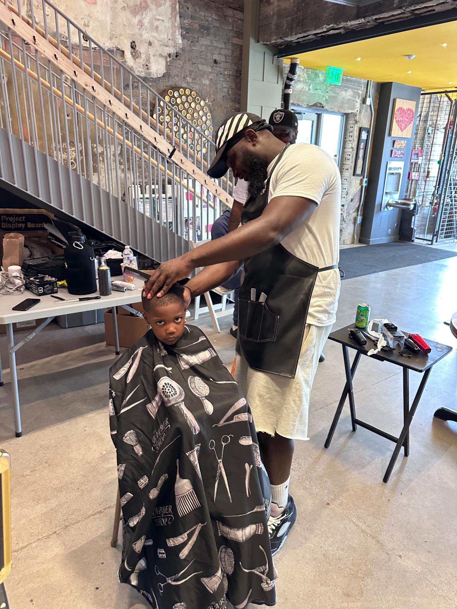 Barber giving a free haircut to a child at the Fresh and Fly Back-to-School Bash